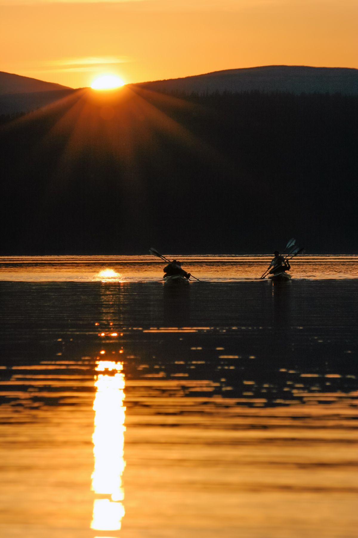 Group of friends returned to the lake by canoe after a hike up the mountain across the lake. Lake Bolshoe Glubokoe (Big Deep), Kola Peninsula, Russia.