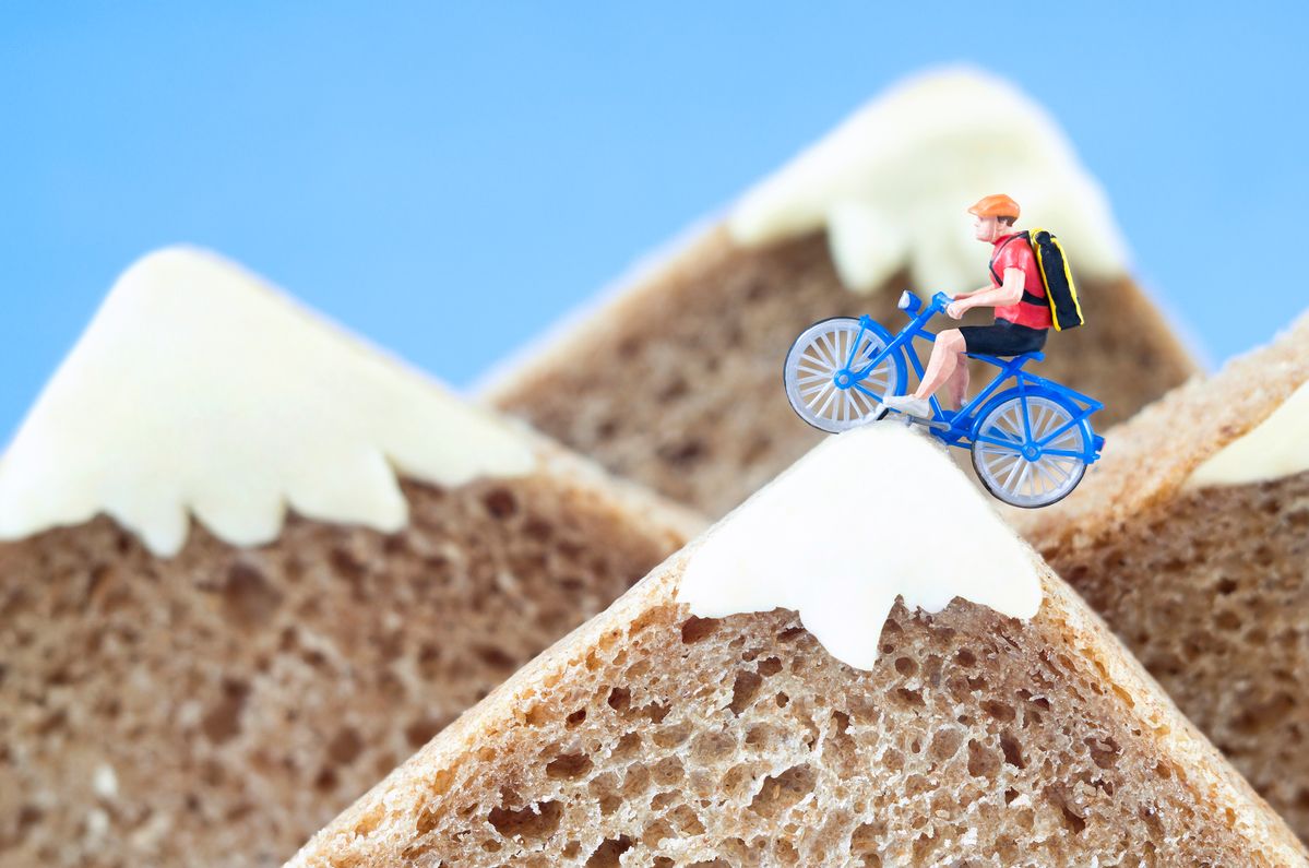 A toy cyclist is taking a ride on mountains, made of rye bread and creamy cheese. Ecotourism and healthy eating concept. All the special effects are real. I used H0 models to create this scene.